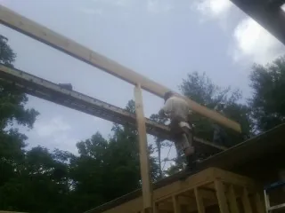 Carpenter setting a ridge beam over a new addition frame — Ice Dam Removal by Roofing Brothers in Stokesdale