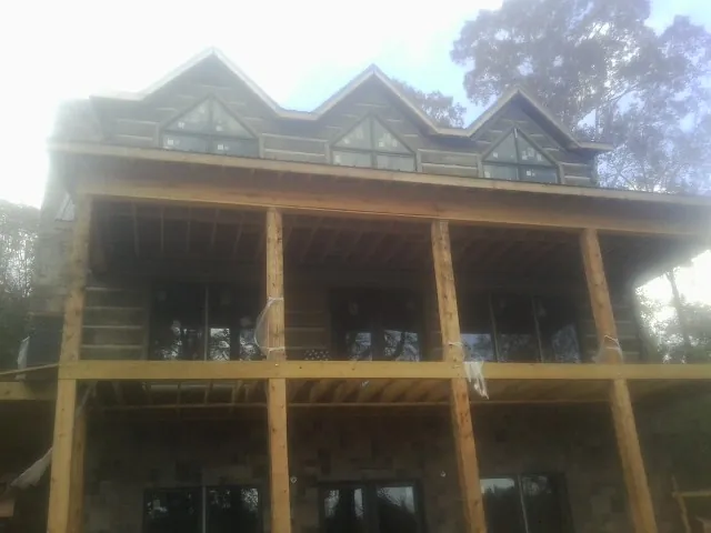 Dormers and porch framing on a large log home under construction — Roof Coating work by our crew in Stokesdale