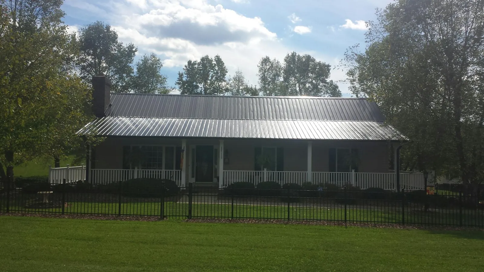 Gray metal roof on a brick ranch with a full width front porch — Gutter Guard Installation work by our crew in Stokesdale